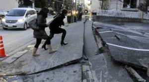 Pedestrians clamber over a piece of collapsed road in Urayasu city, Chiba.