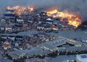 Houses erupt in flame while the Natori river surges over the surrounding area in Natori city, Miyagi Prefecture, northern Japan.